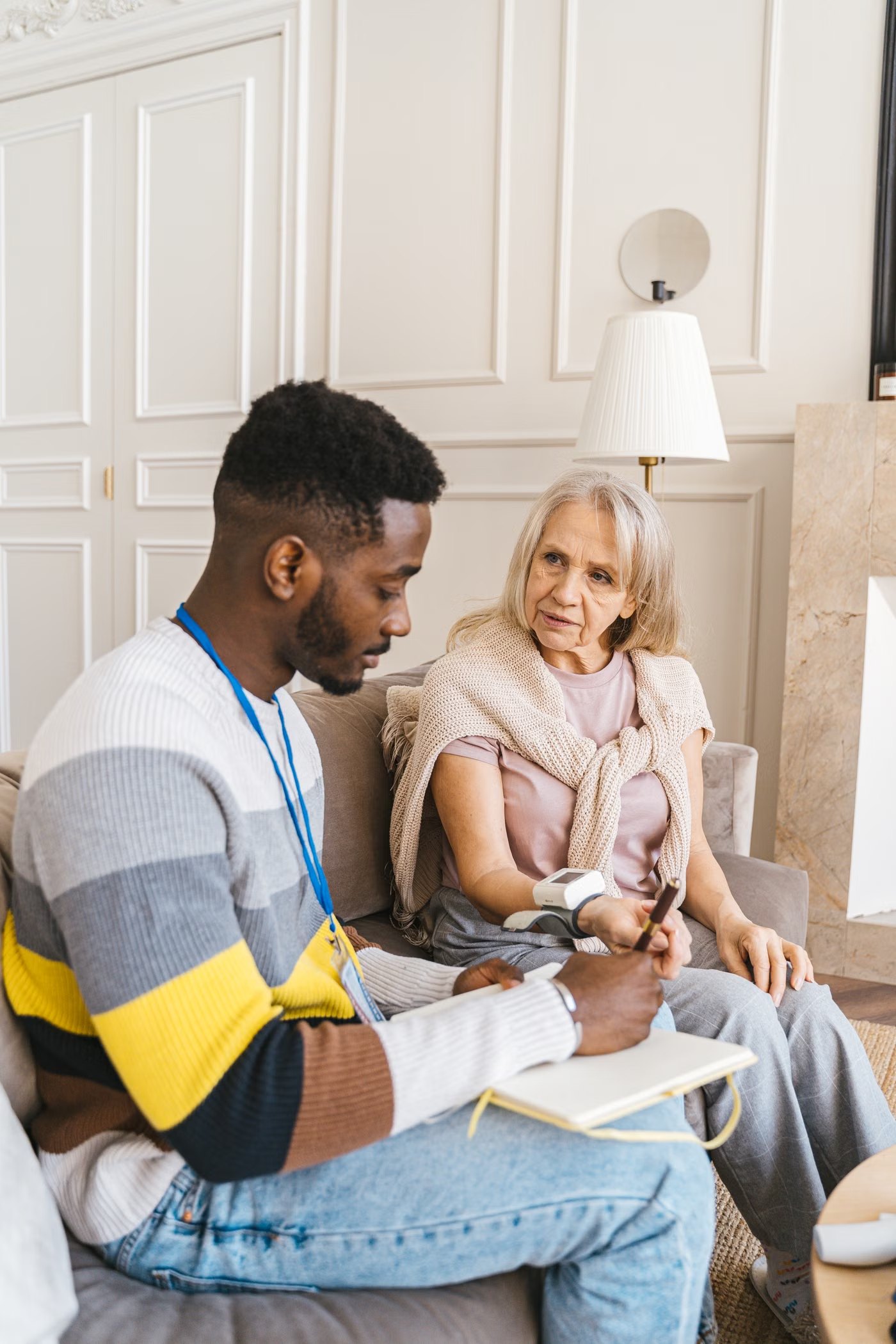 A caregiver checking in with a senior woman at her kitchen table