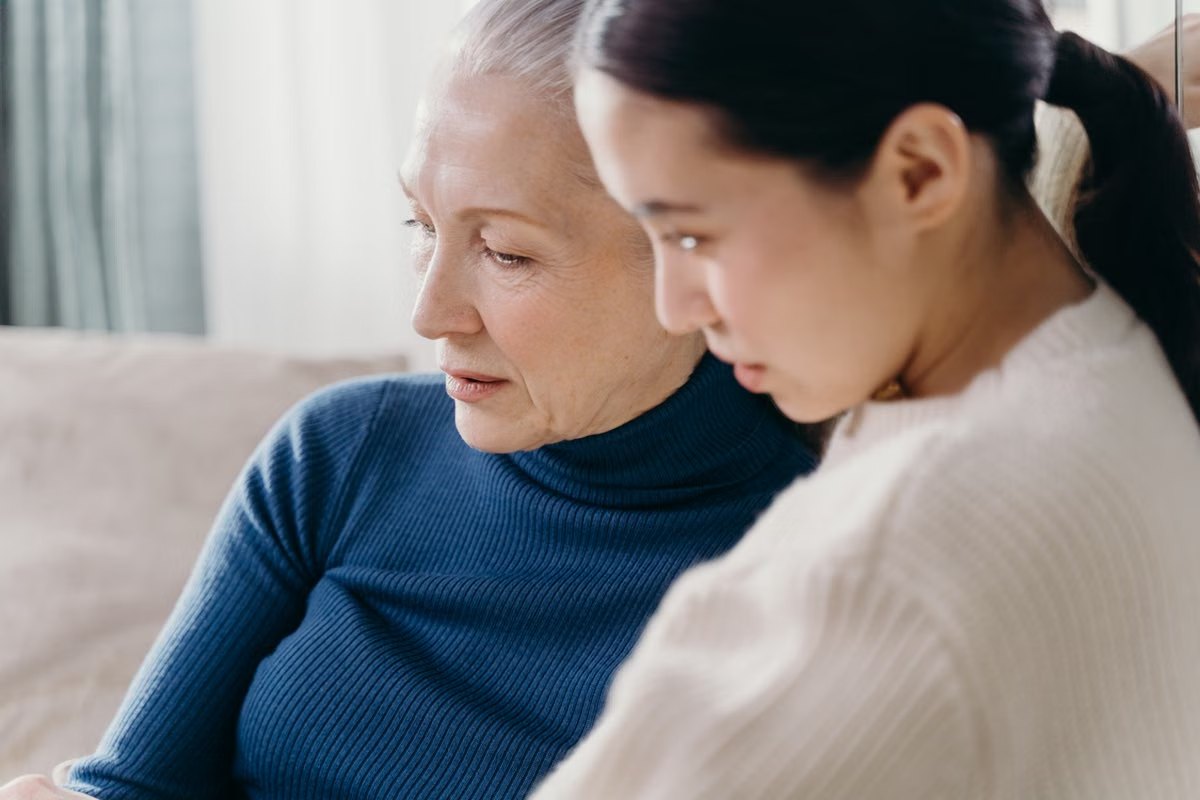 A caregiver sitting close to a senior woman, listening