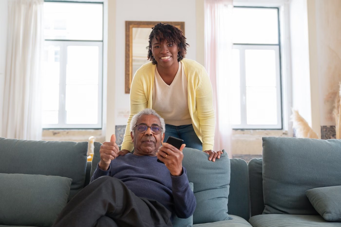 A caregiver and a smiling senior man sharing an easy moment in his living room